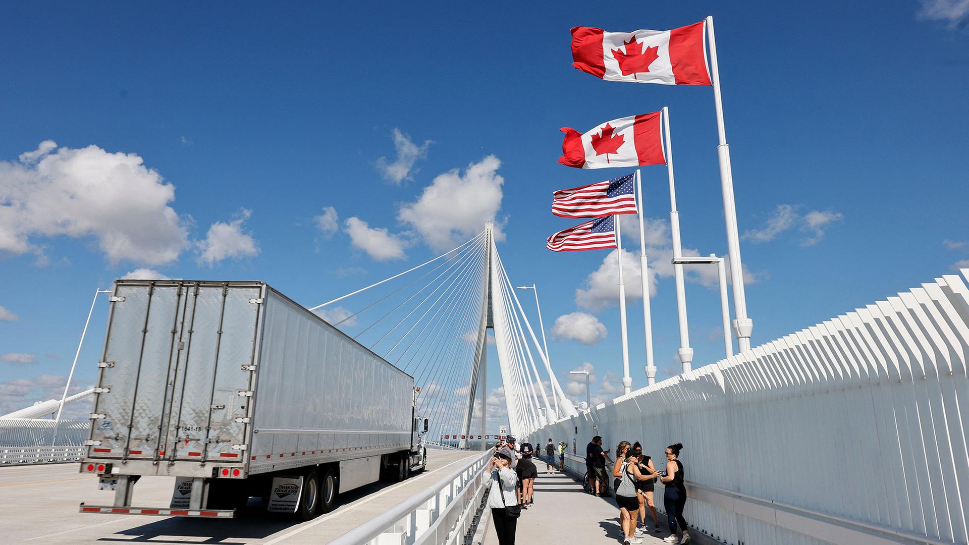 Ein Lkw überquert eine Brücke, auf der die Flaggen der USA und Kanadas wehen. | AFP