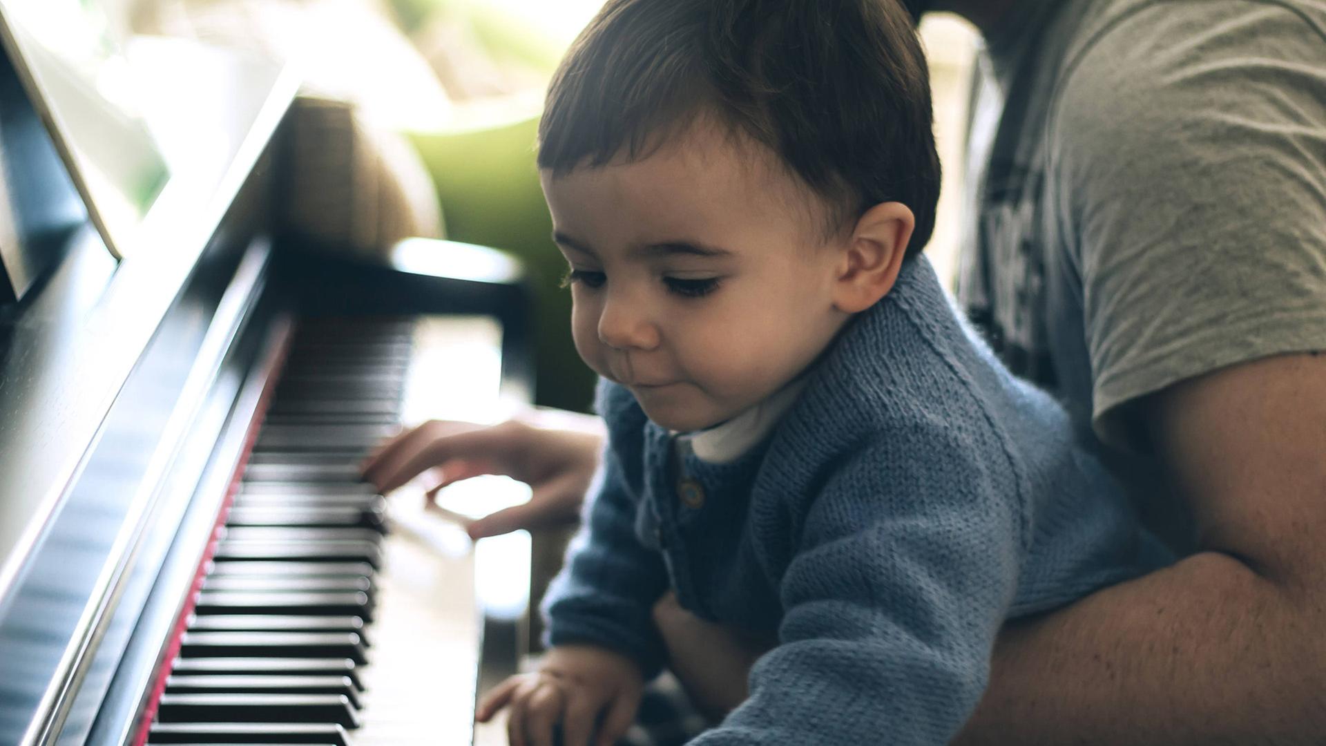 Ein Kleinkind spielt mit seinem Vater Klavier. | imago/Westend61