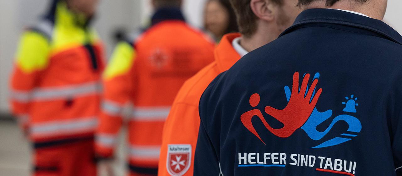 Ein Rettungssanitäter trägt ein Hemd mit der Aufschrift "HELFER SIND TABU" auf dem Rücken.