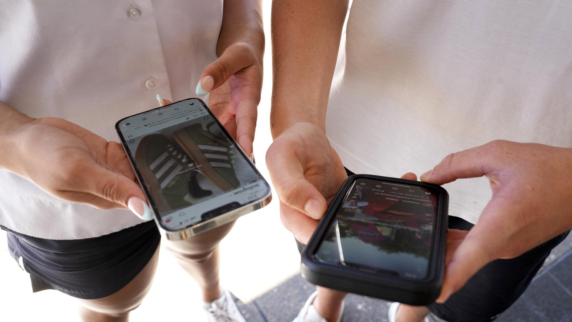 Jugendliche in Australien halten ihr Smartphones in den Händen. | AP