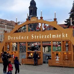 Ein sehr großer Schwibbogen mit der leuchtenden Aufschrift "Dresdner Striezelmarkt".