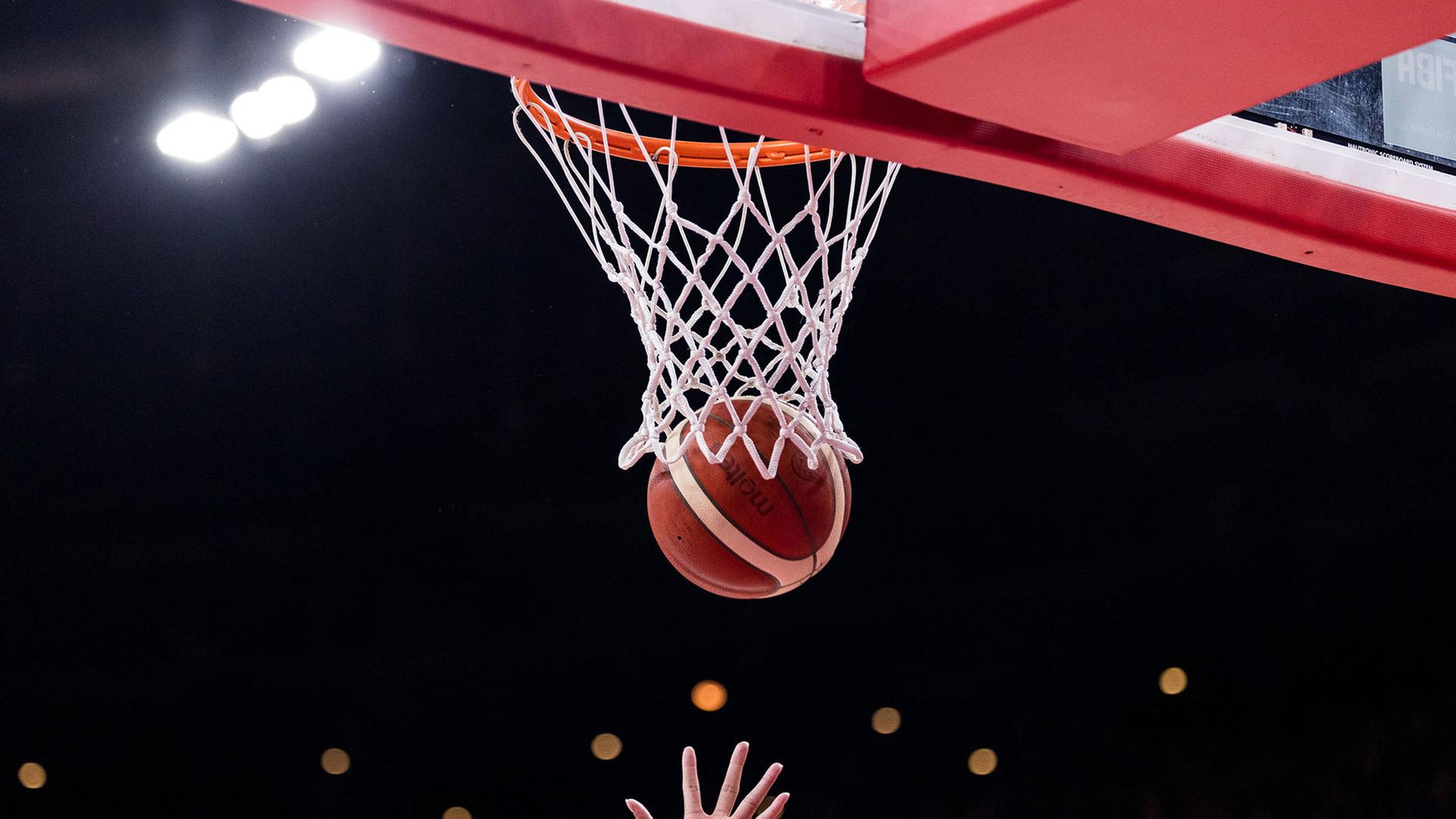 Hände einer Basketballspielerin am Ball vor dem Korb | IMAGO / Beautiful Sports