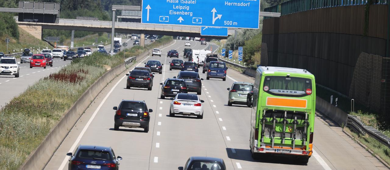 Ein Reisebus und zahlreiche Pkw fahren über eine Autobahn.