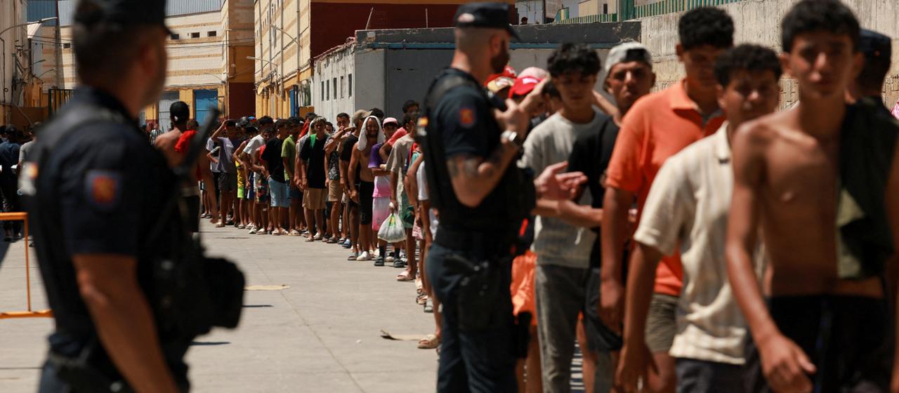 Migranten stehen bei einer NGO in Ceuta Schlange, um Essen zu bekommen.