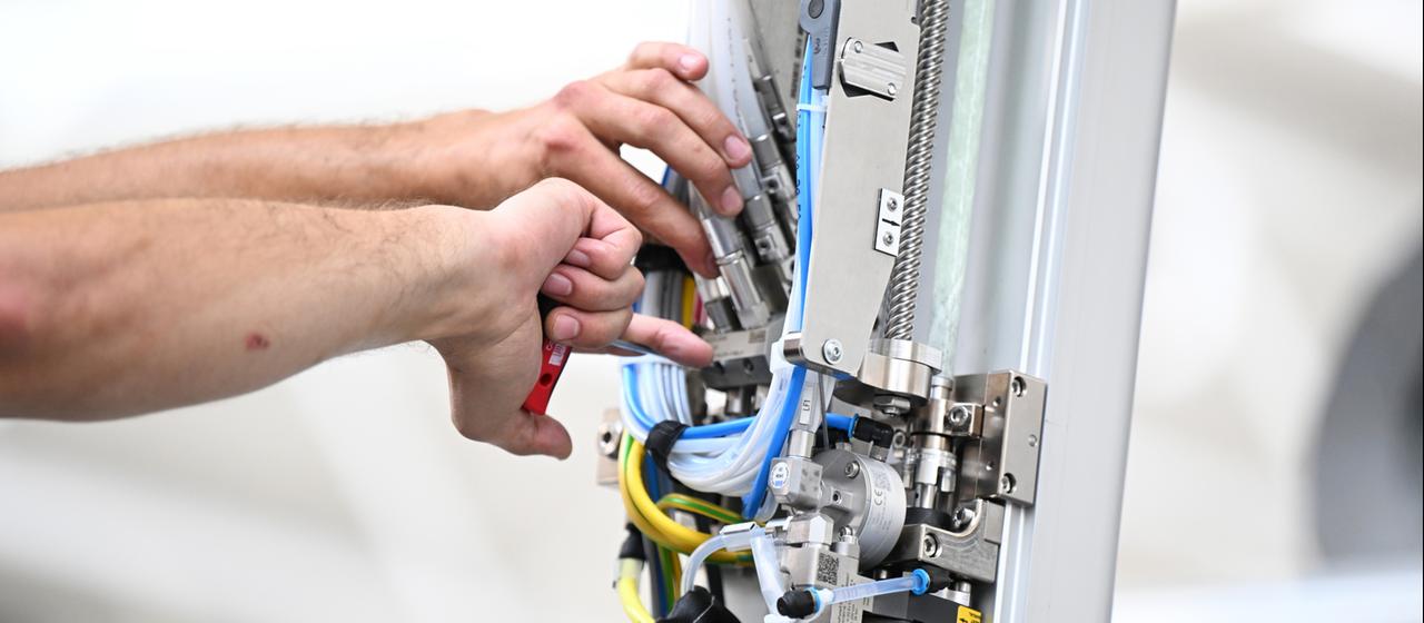 Ein Arbeiter montiert einen Roboterarm an einer Lackieranlage