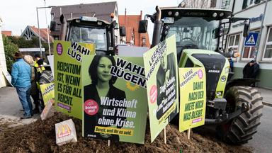 Plakate mit der Aufschrift "Wahl Lügen" stecken während einer Demonstration vor der Stadthalle in Biberach zum politischen Aschermittwoch der Grünen in einem Misthaufen.