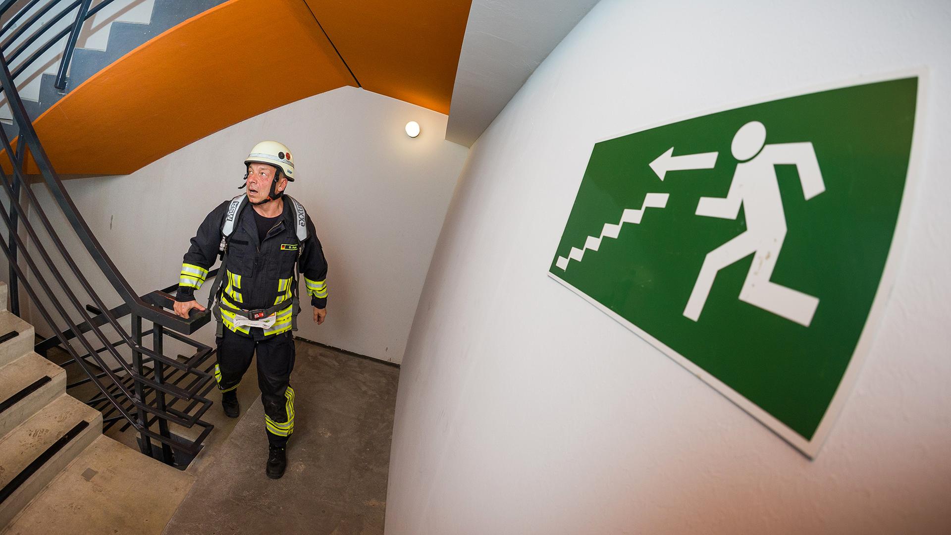  Ein Feuerwehrmann läuft in einem Treppen an einem Notausgangsschild vorbei. | dpa