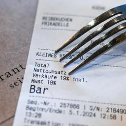Ein Kassenbon mit einer Mehrwertsteuer von 19 Prozent für Speisen und Getränke liegt auf einem Restauranttisch.
