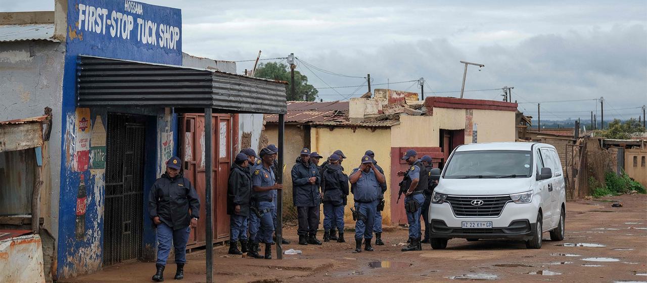 Polizisten und Polizistinnen stehen vor einem Gebäude.