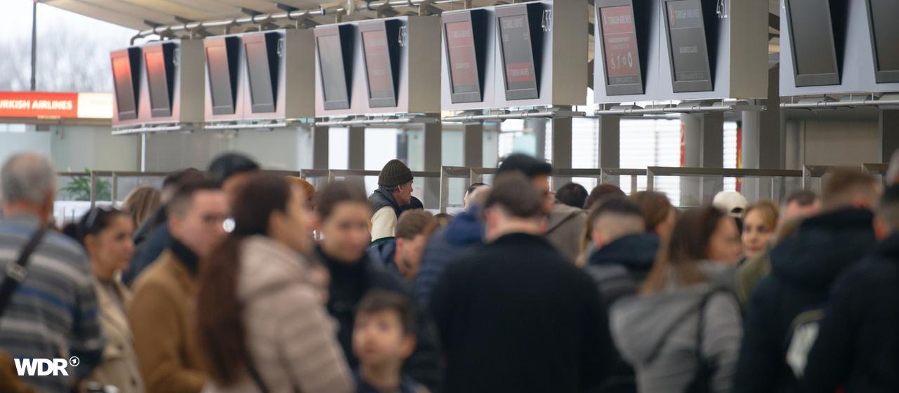 Passengers are queuing at check-in counters at Cologne/Bonn Airport.