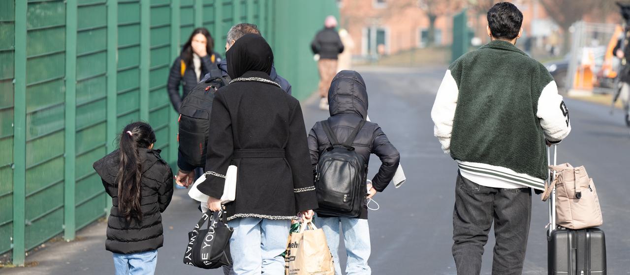 Flüchtlinge gehen in der hessischen Erstaufnahmeeinrichtung für Flüchtlinge in Gießen zu einer Unterkunft.