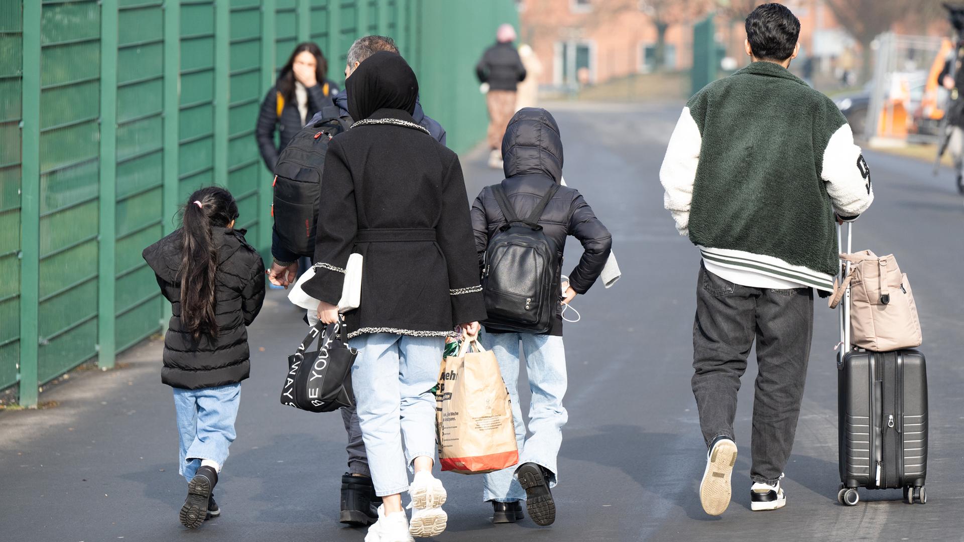 Flüchtlinge gehen in der hessischen Erstaufnahmeeinrichtung für Flüchtlinge in Gießen zu einer Unterkunft. | picture alliance/dpa