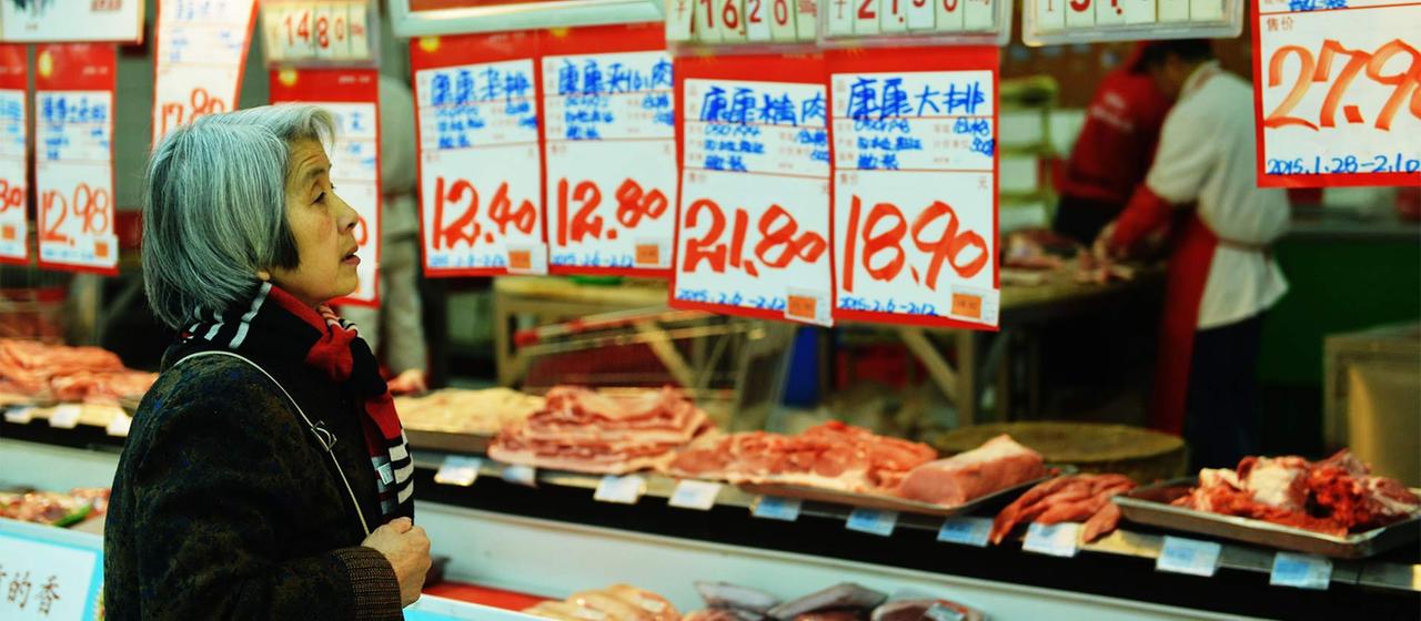 Kundin zwischen Preisschildern in einem Supermarkt, Hangzhou, China.