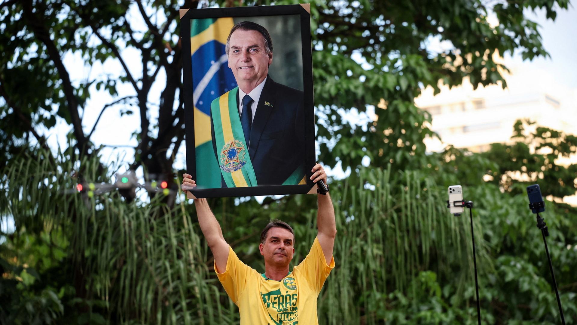 Flávio Bolsonaro hält ein Bild Jair Bolsonaros in die Höhe | REUTERS