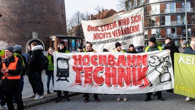 Hochbahnmitarbeiter stehen hinter einem Transparent mit der mit der Aufschrift «Ohne Streik wird sich nichts verändern».