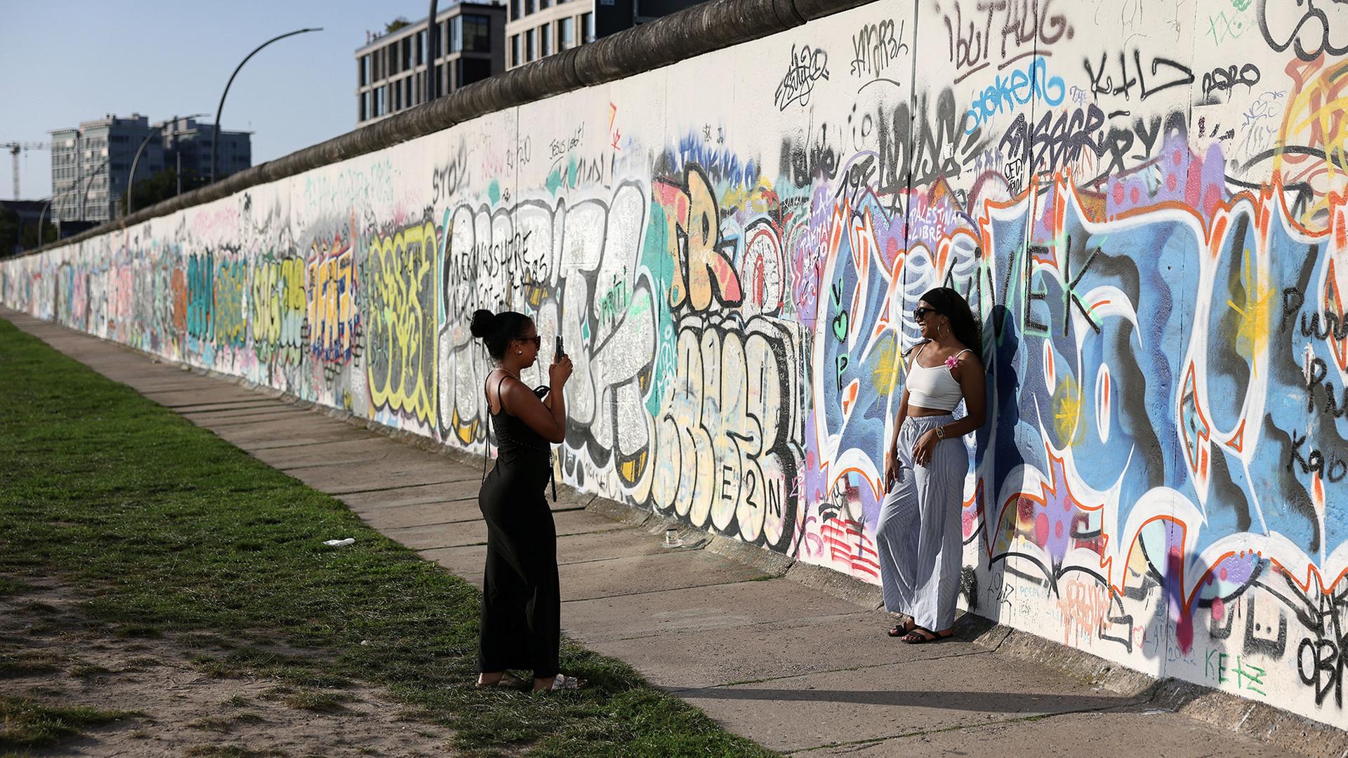 Zwei Frauen machen Fotos an der East Side Gallery in Berlin. | REUTERS