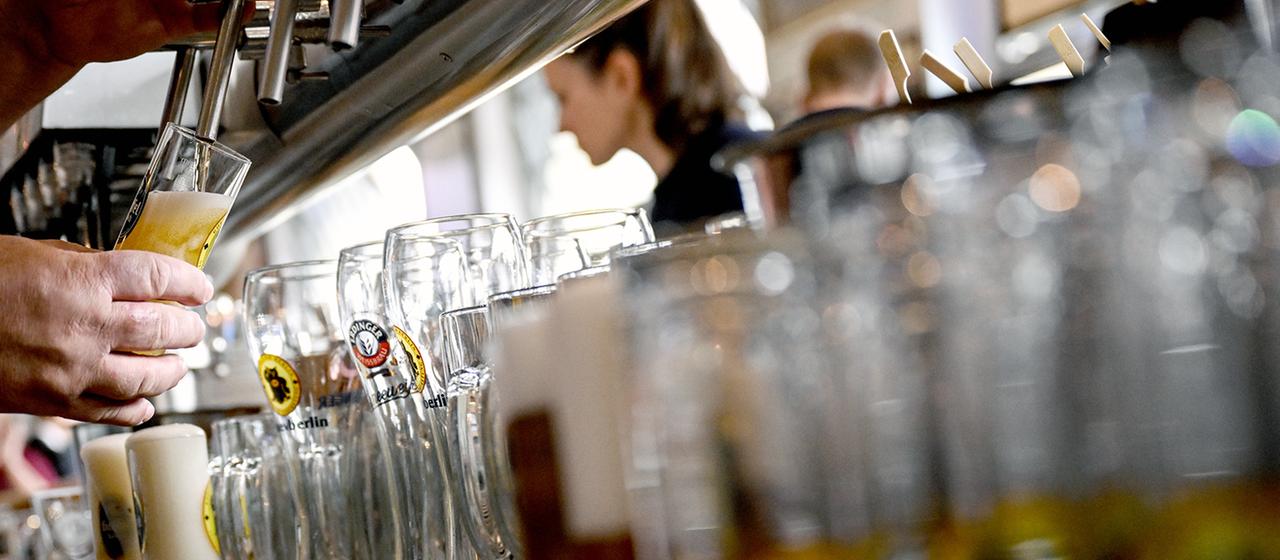 Ein Barkeeper zapft Bier.