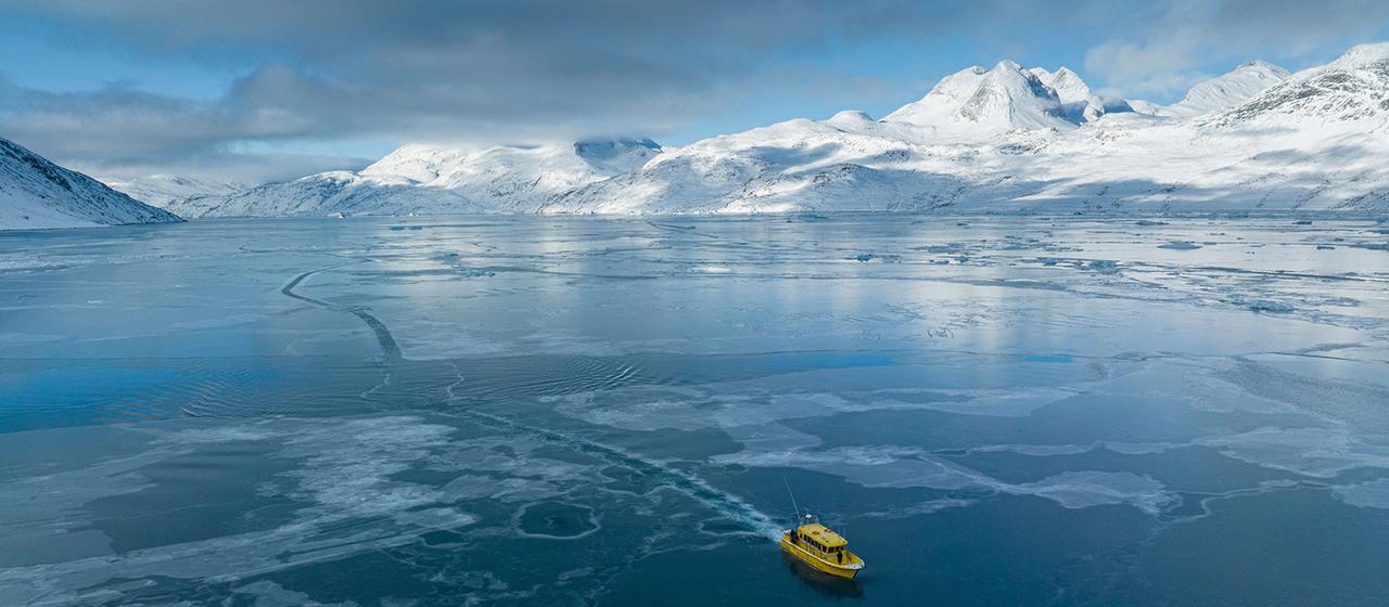 Ein Boot fährt durch einen zugefrorenen Meeresarm.