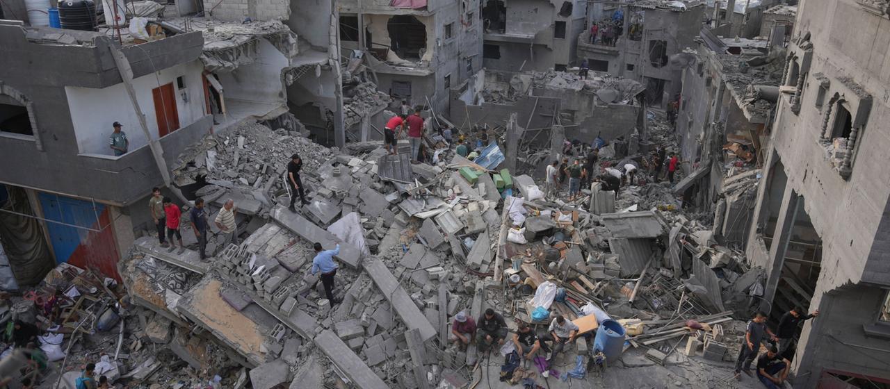 Menschen durchsuchen die Trümmer eines Gebäudes im Gazastreifen.