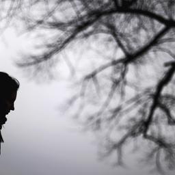 Eine Frau geht bei grauem Himmel in der kalten Jahreszeit spazieren. 