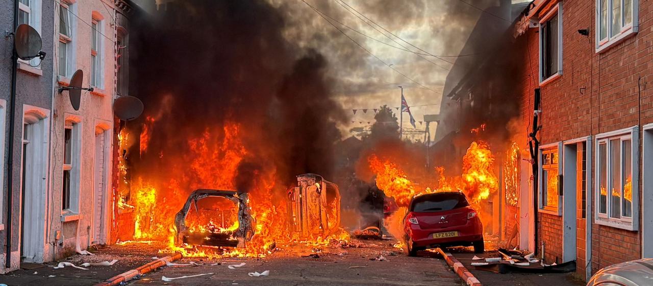 Von Demonstranten in Brand gesetzte Fahrzeuge brennen in der Lendrick Street im Osten von Belfast, Nordirland.