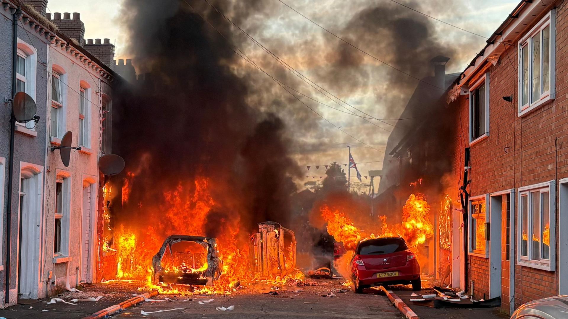 Von Demonstranten in Brand gesetzte Fahrzeuge brennen in der Lendrick Street im Osten von Belfast, Nordirland. | PA/PA via AP