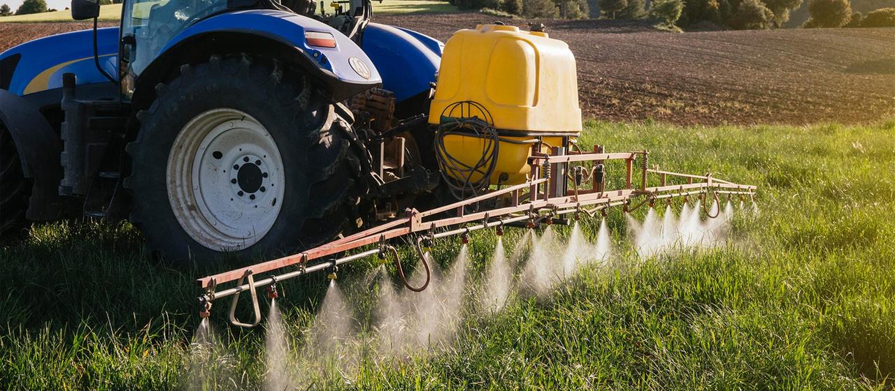 Mit einem Traktor wird Düngemittel auf einem Feld ausgebracht.