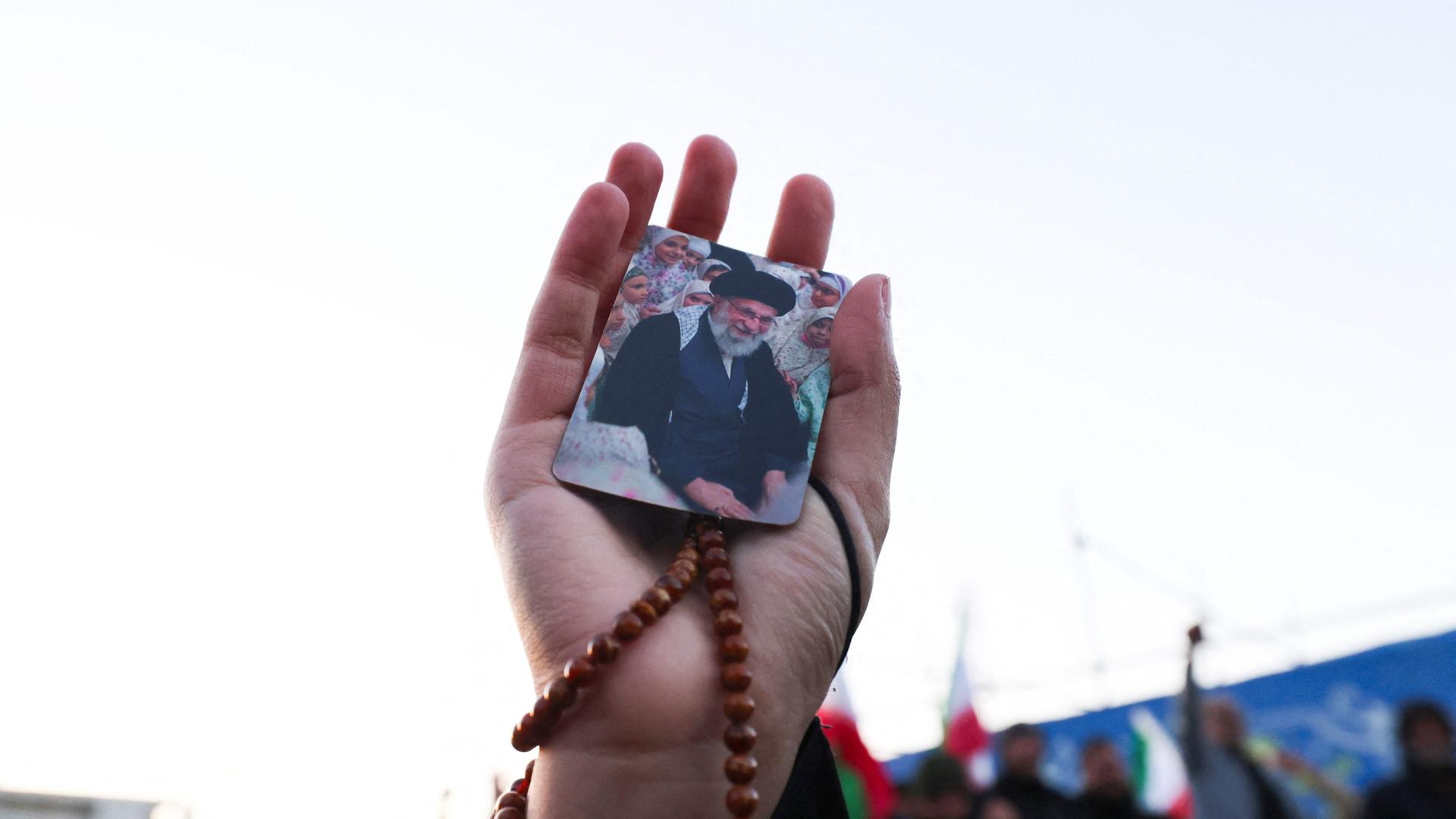 Eine Person hÃ¤lt ein Bild von Irans oberstem FÃ¼hrer Ayatollah Ali Chamenei auf einem Platz in Teheran. | AFP