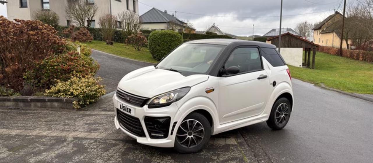 Ein Mopedauto steht in einer Straße.