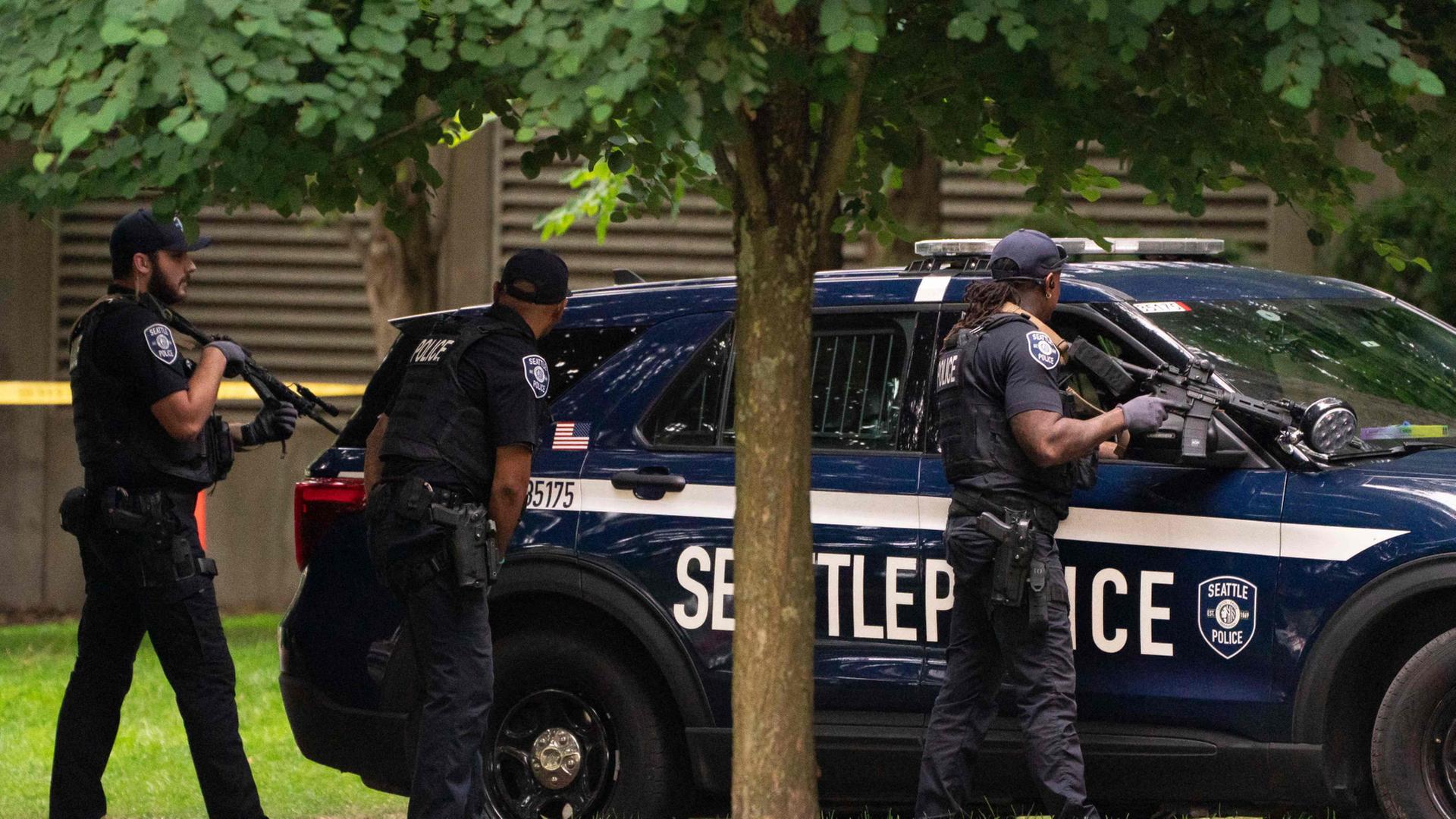 Polizisten stehen bewaffnet hinter einem Polizeiauto in Seattle. | Getty Images via AFP