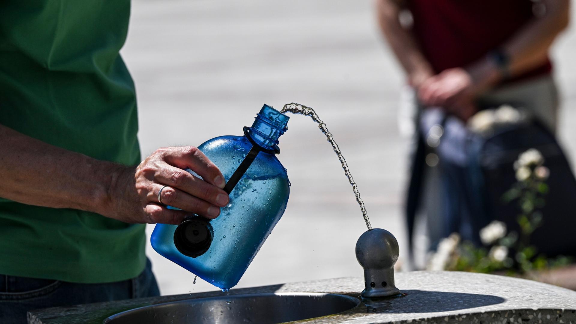 Ein Mann nutzt auf dem Gendarmenmarkt einen Wasserspender, um seine Trinkflasche aufzufüllen.  | Jens Kalaene/dpa