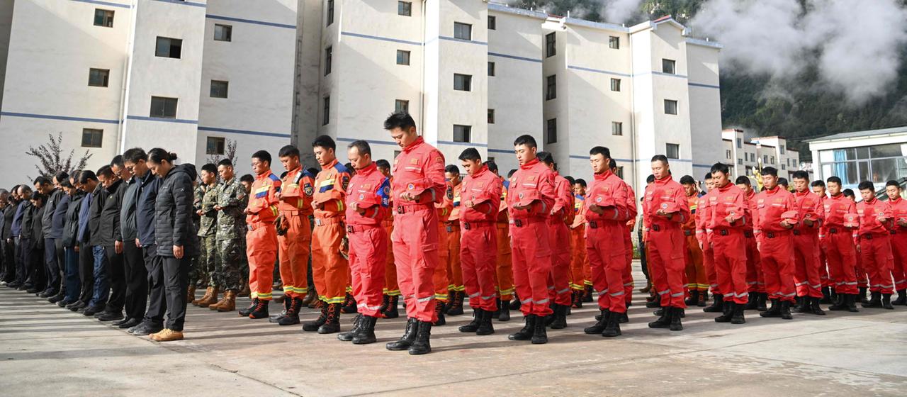 Trauernde nehmen an einer Gedenkfeier für die Opfer eines Schlammlawinenunglücks auf der Polizeiwache des Hafens von Gyirong in der westchinesischen Region Tibet teil.