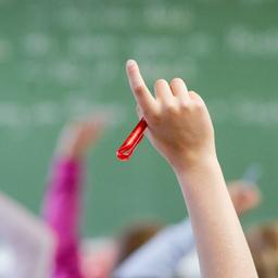Nahaufnahme des Arms einer Schülerin oder eines Schülers, der sich im Klassenzimmer meldet.