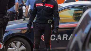 Ein Carabinieri steht vor einem Einsatzfahrzeug.