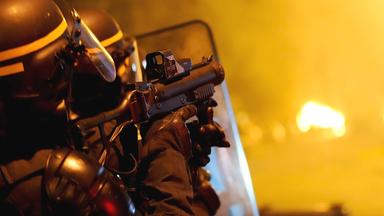 Ein Polizist schießt mit Tränengas.