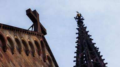 Ein Kreuz ist an der Fassade des Freiburger Münsters zu sehen.