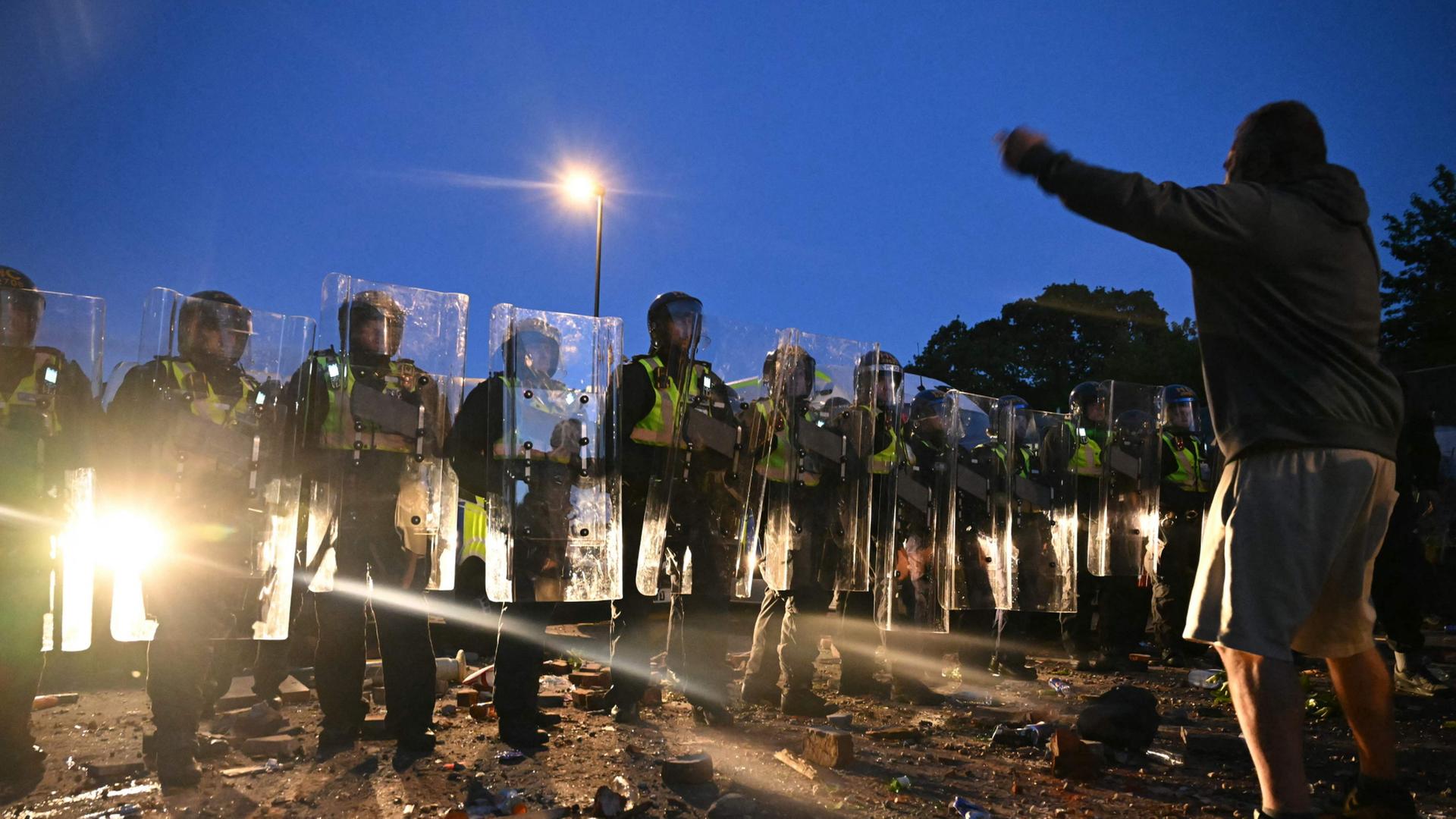 Ein Mann mit drohender Geste steht Polizisten gegenüber | AFP