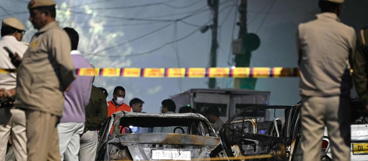 Sicherheitskräfte stehen neben ausgebrannten Autos am Ort der Explosion in der indischen Hauptstadt Neu Delhi