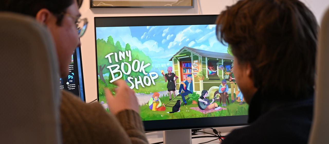 David Zapfe-Wildemann und Raven Rusch sitzen vor einem Bildschirm, auf dem die Startseite des Spiels 