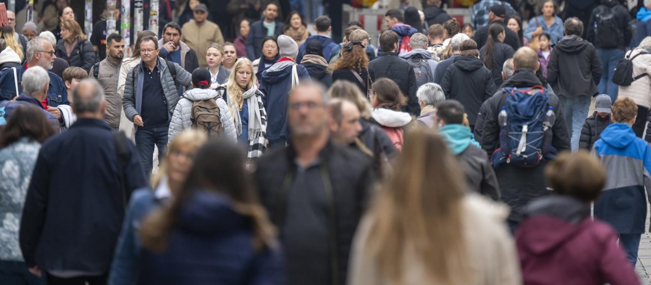 Passanten laufen durch eine Fußgängerzone in München.