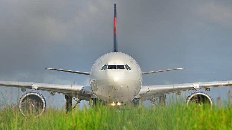 Ein gelandeter Jet hinter einer Wiese am Rand des Frankfurter Flughafens Fraport.