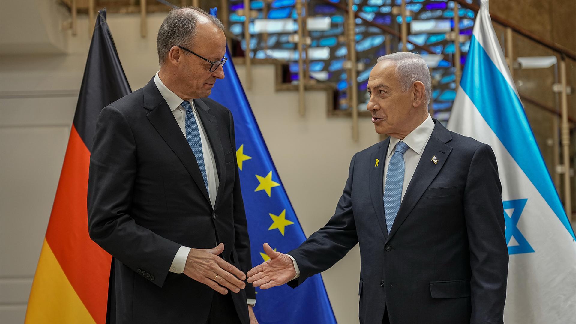 Friedrich Merz (l) steht neben Benjamin Netanjahu und reicht ihm die Hand. | dpa