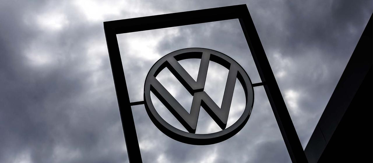 VW-Logo vor dunklen Wolken.