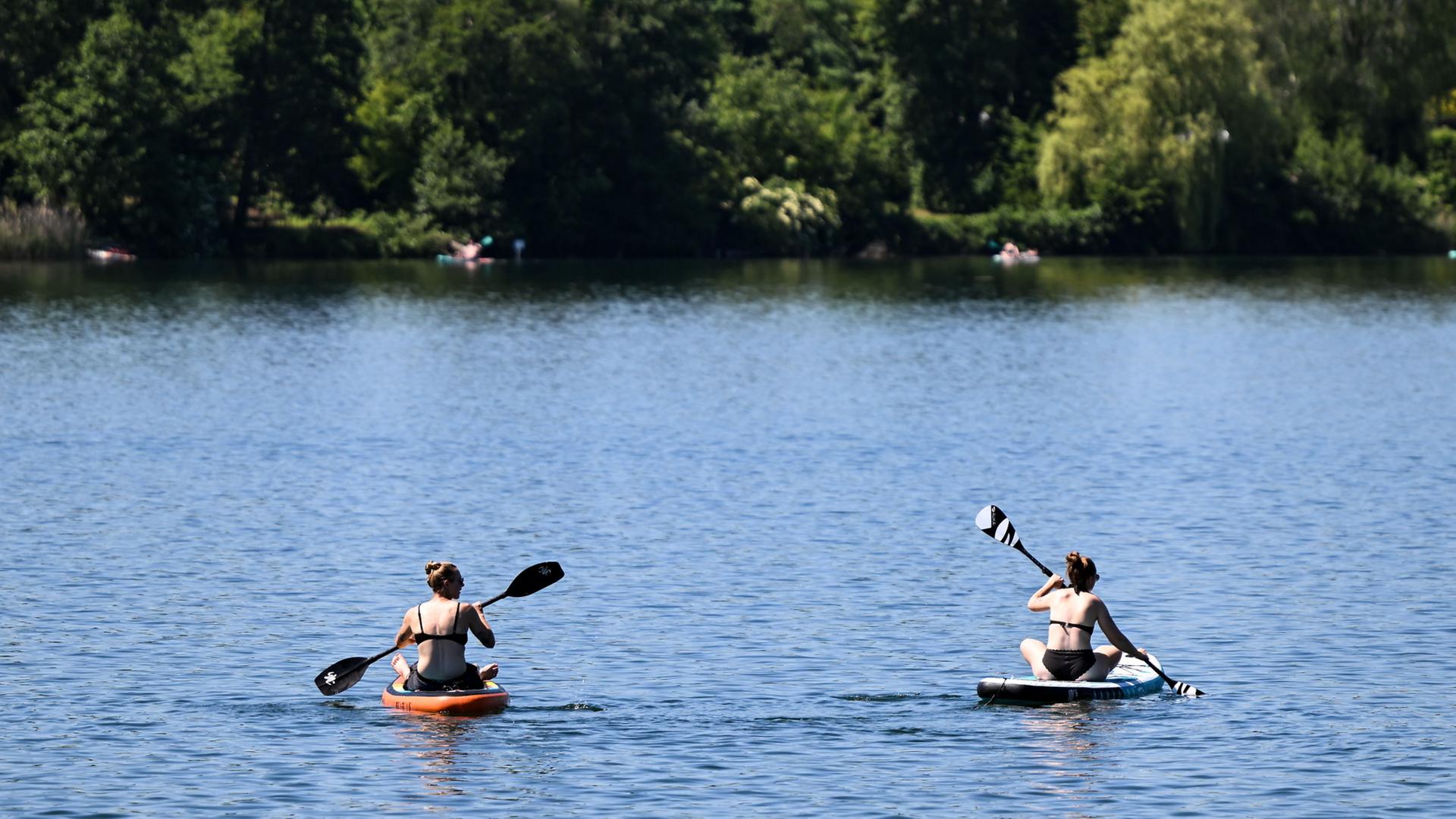 Stand-up-Paddler sind bei sommerlichen Temperaturen auf dem Badesee in Trais-Horloff unterwegs. | Florian Wiegand/dpa