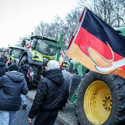 Ein Demonstrationsteilnehmer geht über die Straße des 17. Juni mit einer Deutschlandfahne mit einer Banane darauf.