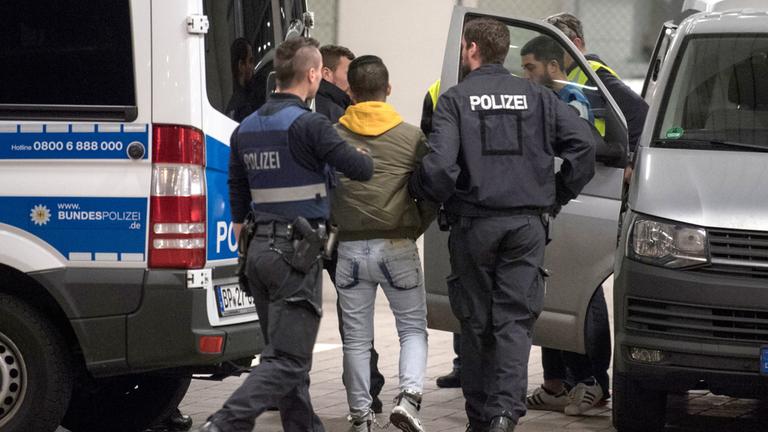  Polizisten bringen einen jungen Mann zur Abschiebung zum Flughafen.