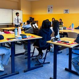 Schülerinnen und Schüler sitzen in einem Klassenraum während eines Unterrichts an einer Privatschule.