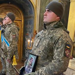 Ukrainische Soldaten halten bei einer Trauerfeier ein Foto eines gefallenen Kameraden.