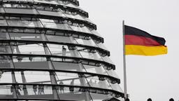 Neben der Reichstagskuppel in Berlin weht eine Flagge der Bundesrepublik Deutschland.