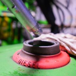 Ein Landwirt betankt ein Fahrzeig in seiner Fahrzeughalle mit Diesel.